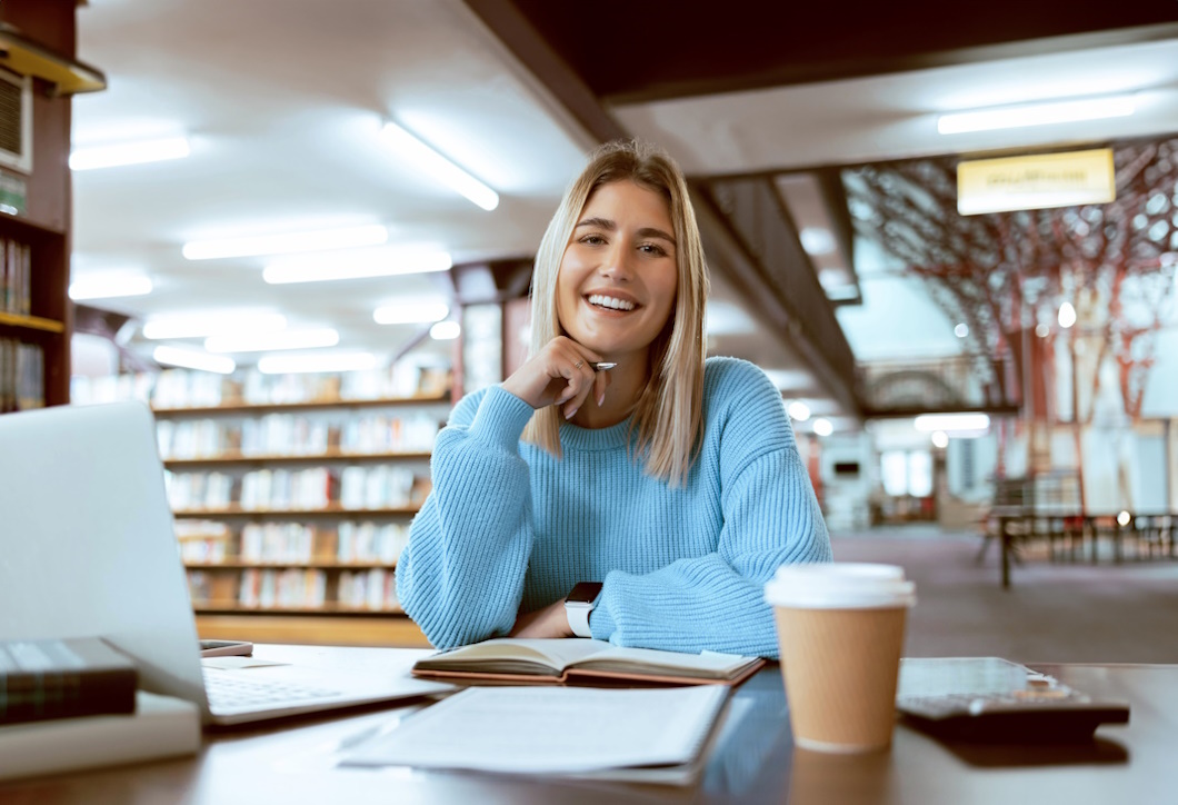 Books, portrait or happy woman in a library reading for knowledge or development for future growth. Scholarship, student or school girl smiles with pride studying or learning college information