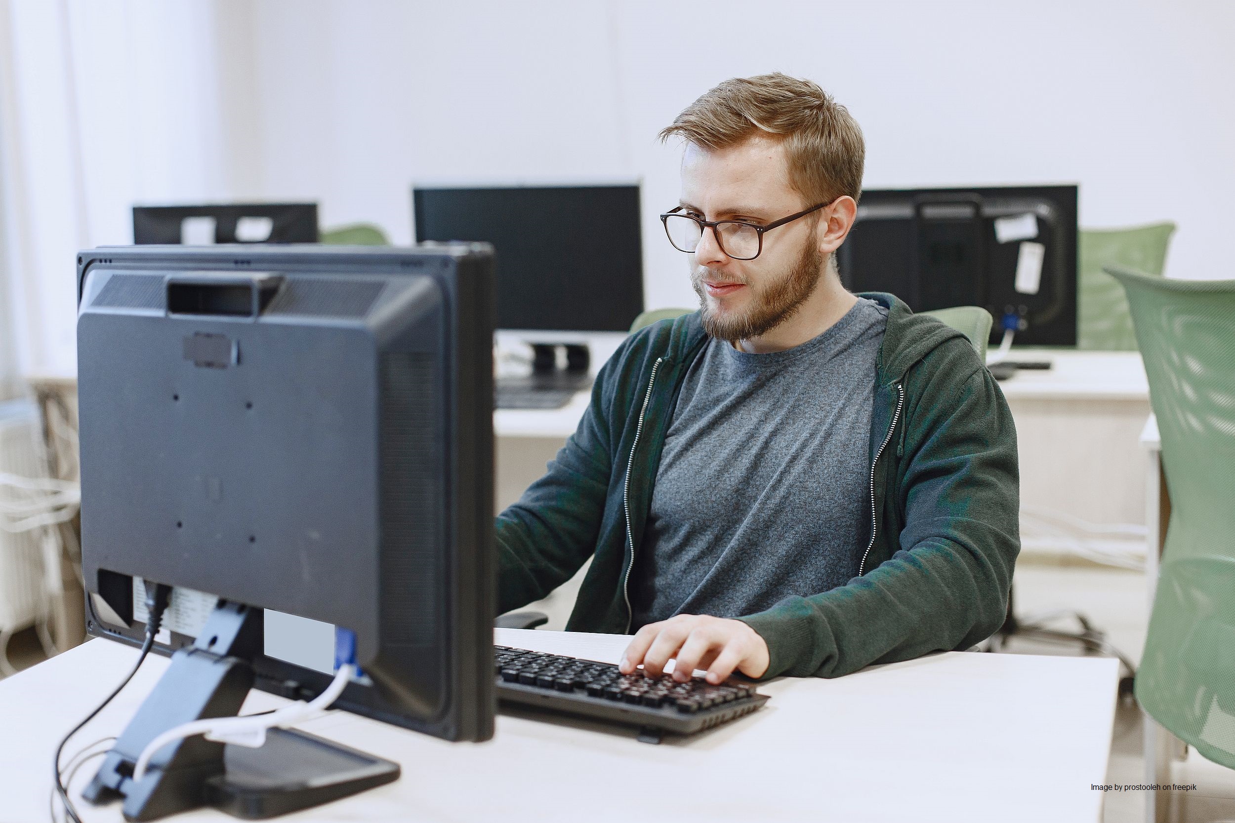 Man with glasses is sitting at the computer.